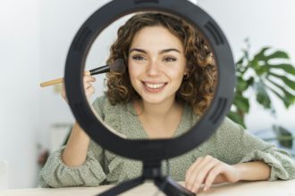 Beauty blogger shoots daily female movies of makeup routine on camera, woman curly hair