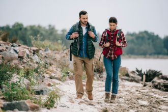 hikers with backpacks walking on sandy beach together