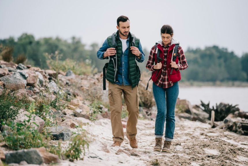 hikers with backpacks walking on sandy beach together