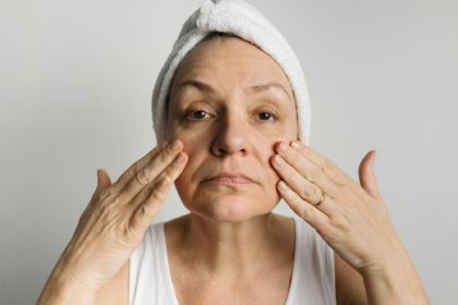 Middle-aged woman lookin in a mirror and checking bags under the eyes, skin and wrinkles. Skincare