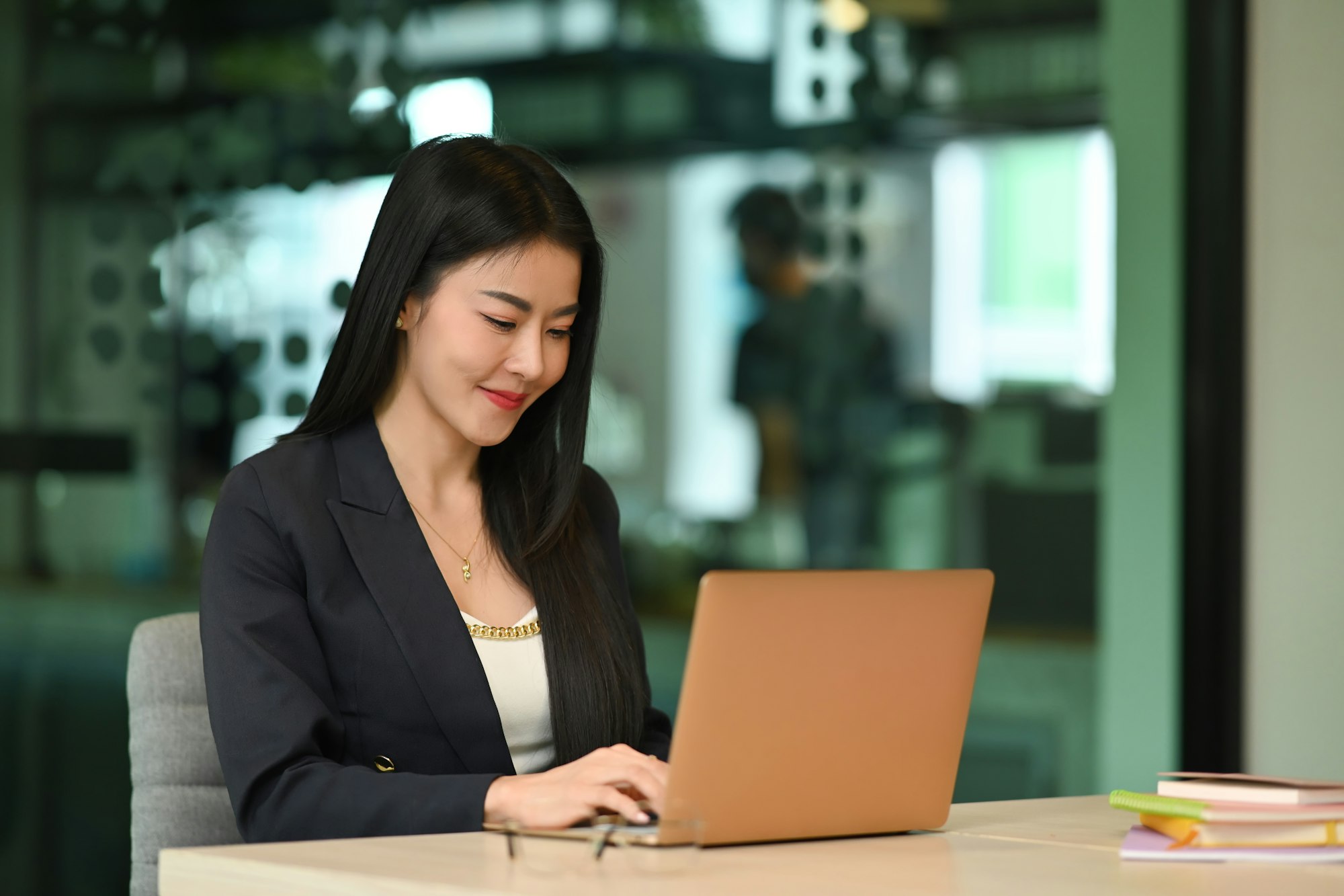 Millennial female entrepreneur using laptop, working on research project in her personal office.